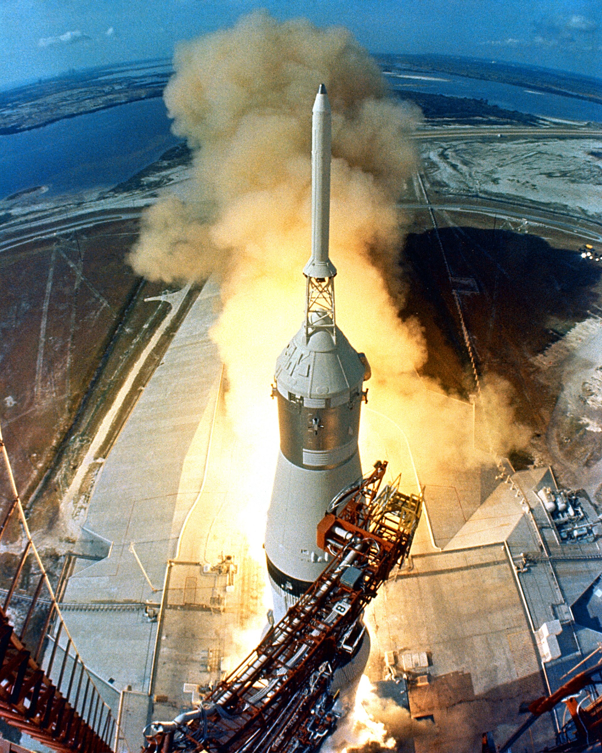 The Apollo 11 Saturn V rocket lifting off from Launch Pad 39A, trailing a bright plume of flame
