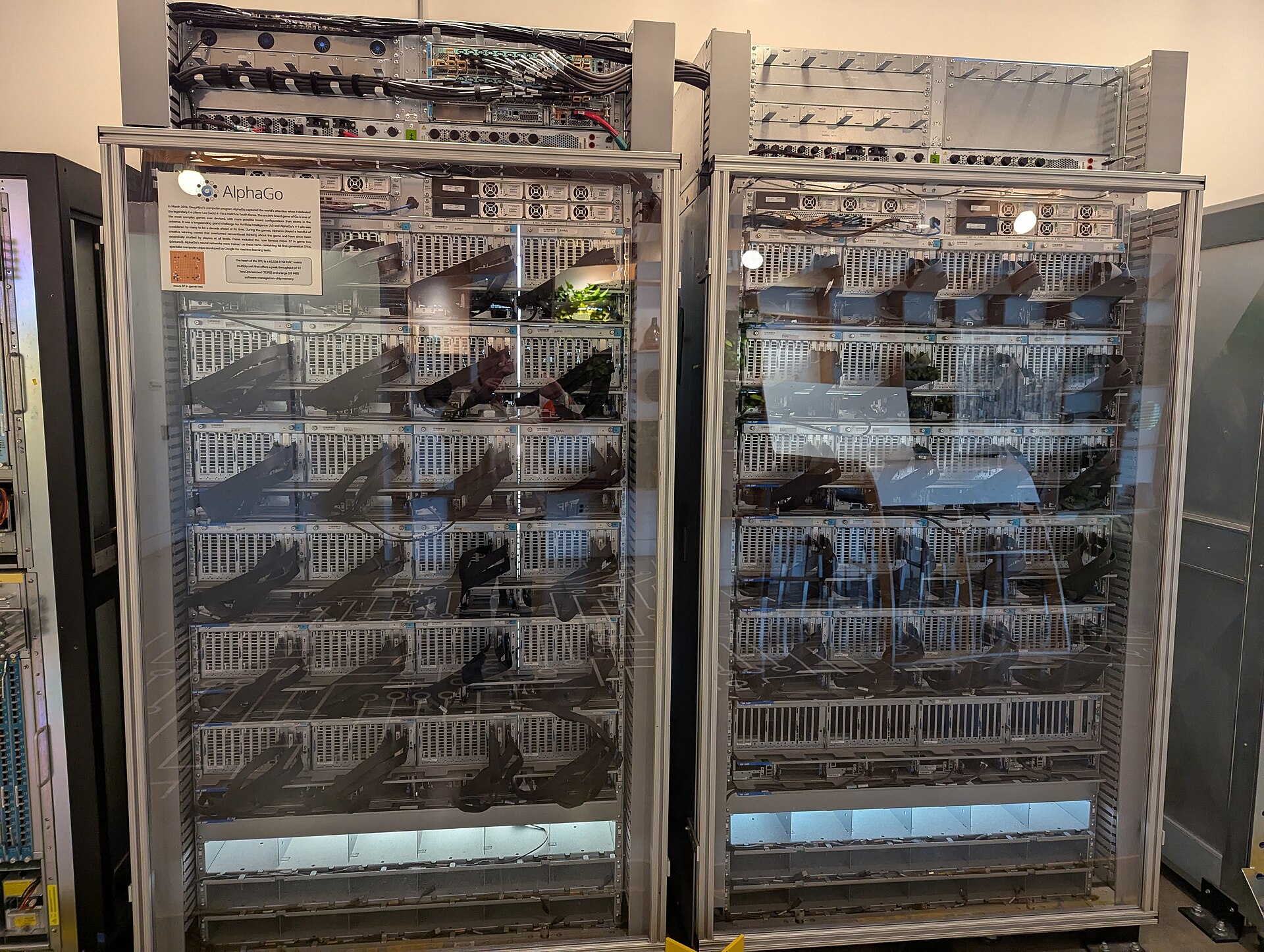 The decommissioned backend rack of AlphaGo, with its AlphaGo museum placard, displayed in a server room setting