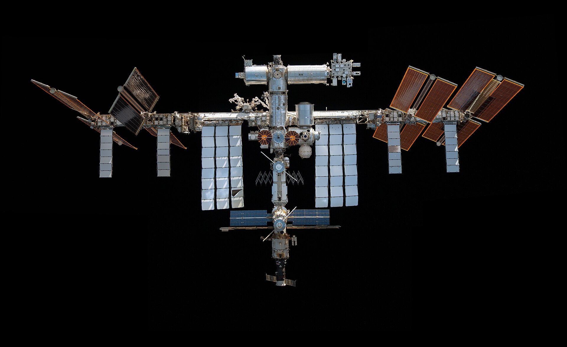 The International Space Station photographed from the SpaceX Crew Dragon spacecraft during a flyaround, with Earth's horizon and black space behind