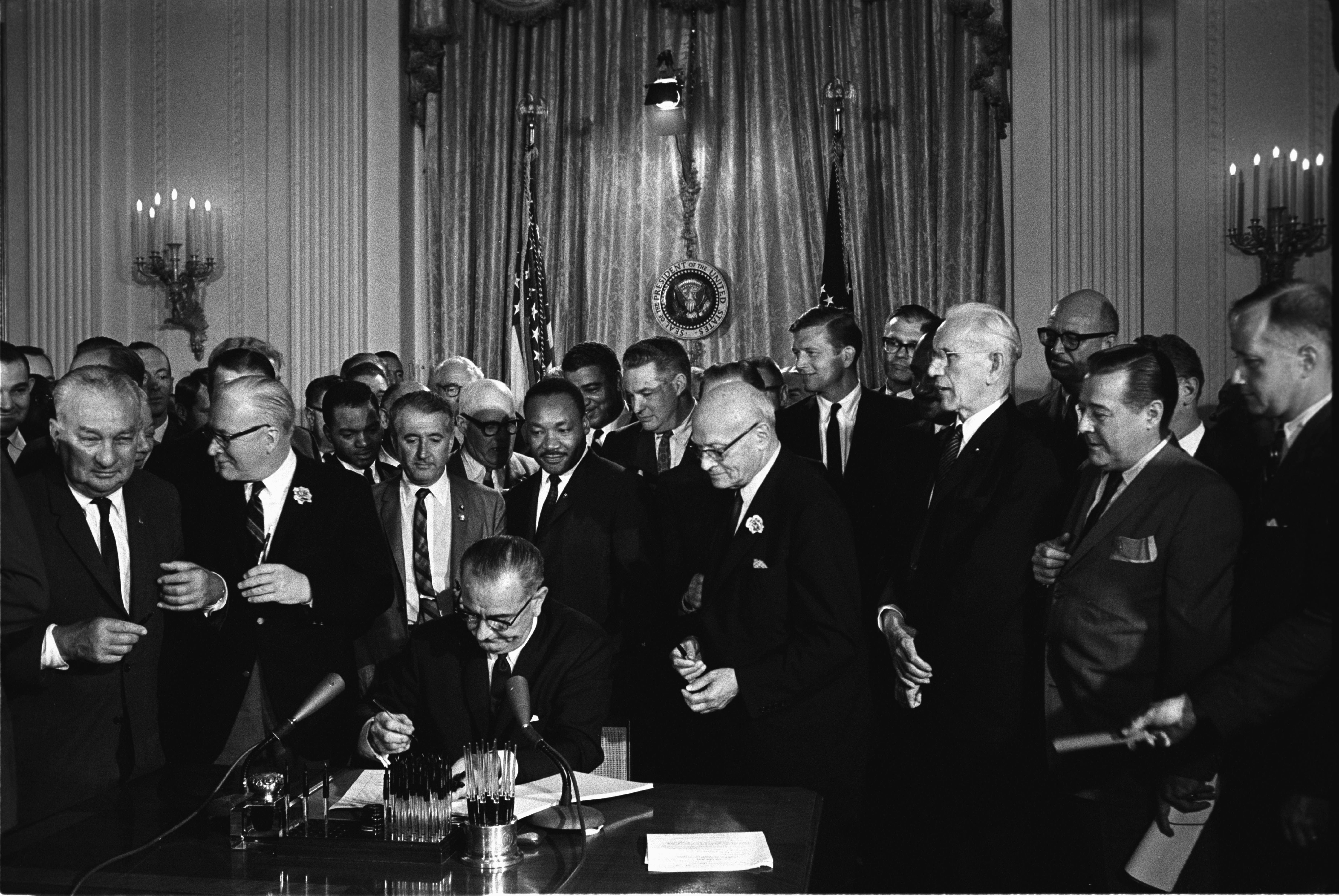 President Lyndon B. Johnson signing the Civil Rights Act of 1964 on 2 July 1964, with Martin Luther King Jr. and other leaders present