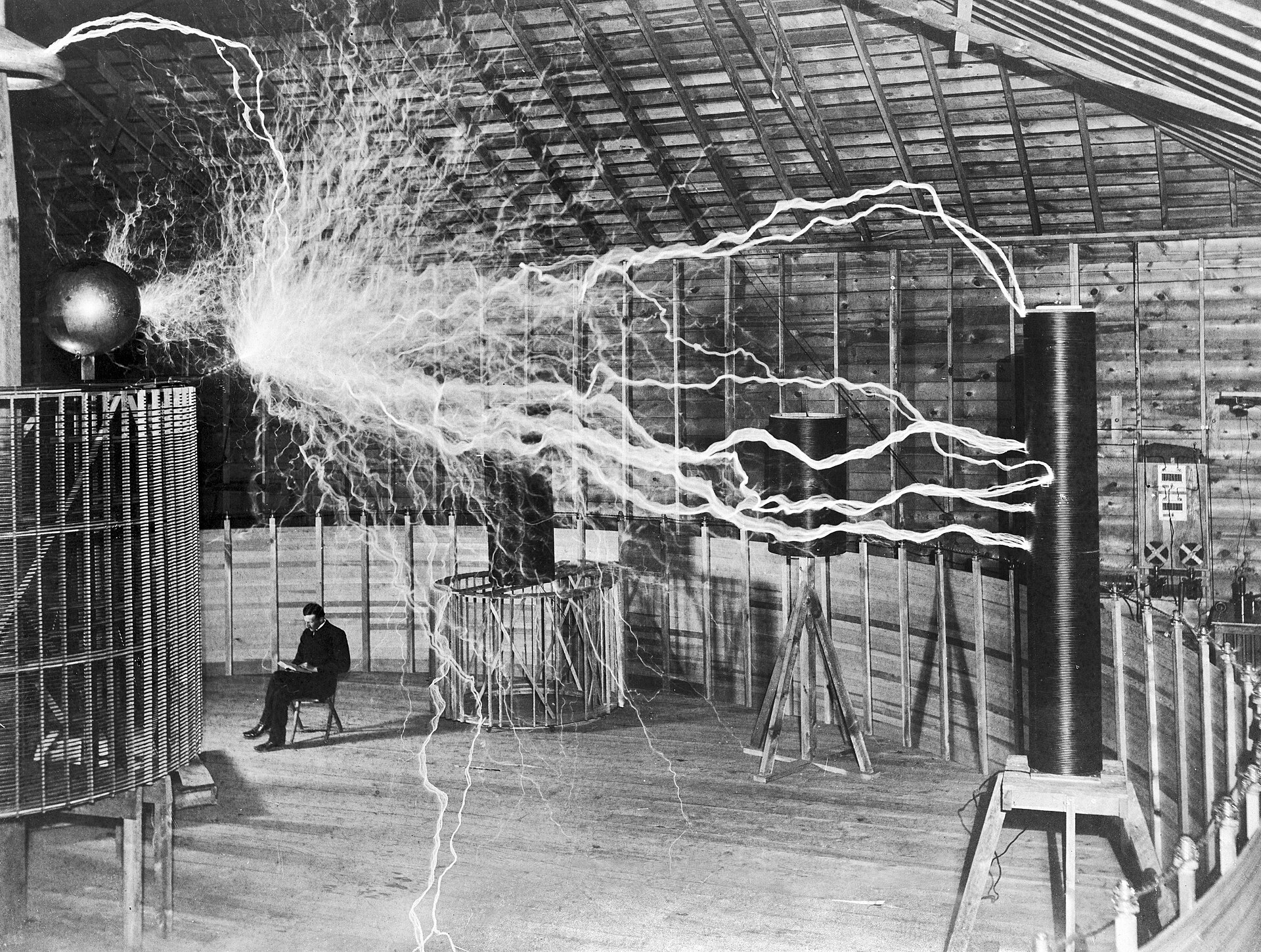 Nikola Tesla seated in his Colorado Springs laboratory amid massive electrical discharges from his magnifying transmitter, 1899