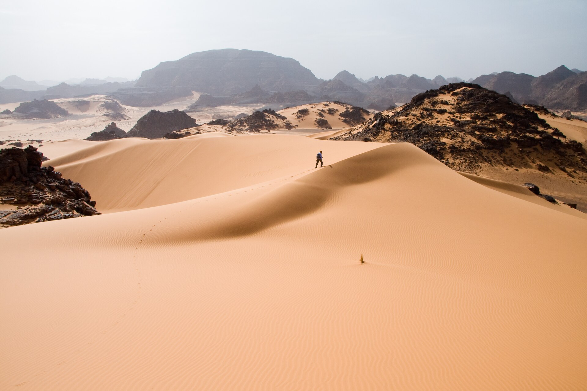 Sand dunes with dark rock outcrops in the Tadrart Acacus, a desert area in western Libya, part of the Sahara