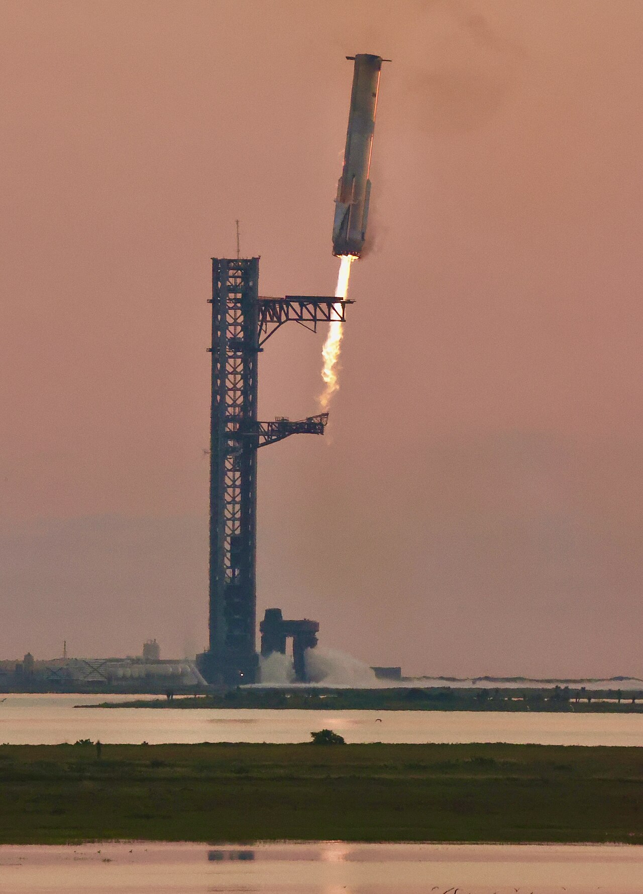 Super Heavy booster descending back toward the launch tower during Starship's fifth flight test, the first-ever booster catch