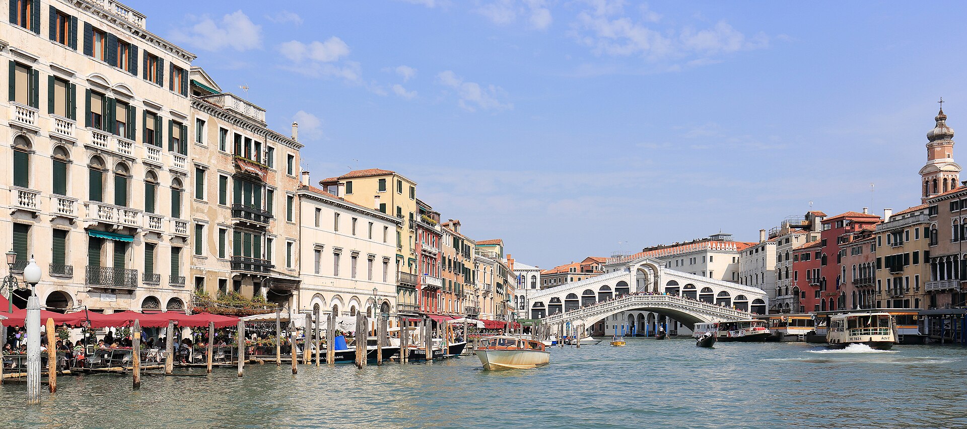 The Grand Canal of Venice curving towards the Rialto Bridge, lined with Renaissance palazzi, with gondolas and water buses on the water